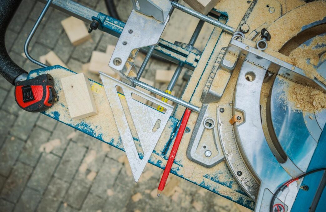 A skilled carpenter uses a table saw surrounded by tools in a sunlit workshop.