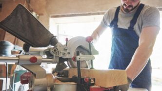 A beautifully arranged woodworking shop featuring a table saw and miter saw, illuminated by sunlight.