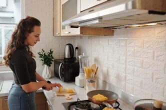 Homeowner installing mosaic tile backsplash in a modern kitchen during DIY project.