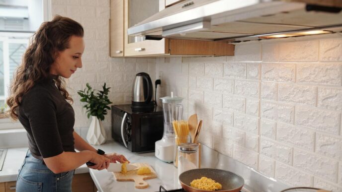 Homeowner installing mosaic tile backsplash in a modern kitchen during DIY project.