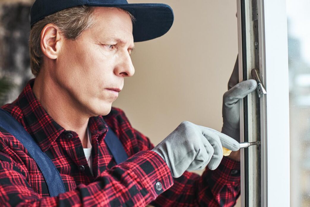 DIY enthusiast replacing a window pane in a sunlit, vintage home, surrounded by tools.